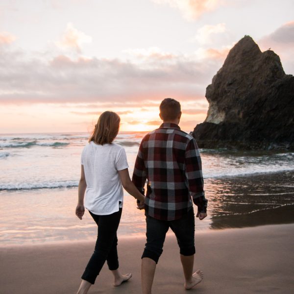 A couple walking hand in hand along the beach at Pendine Carmarthenshire and the sun is setting