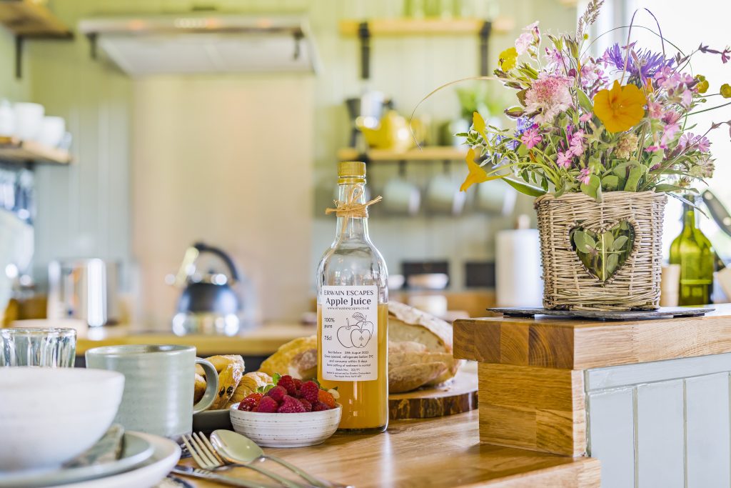 Fully equipped Kitchen with breakfast bar seating inside the Cabin at Erwain Escapes with Apple Juice gifted in the guest welcome hamper