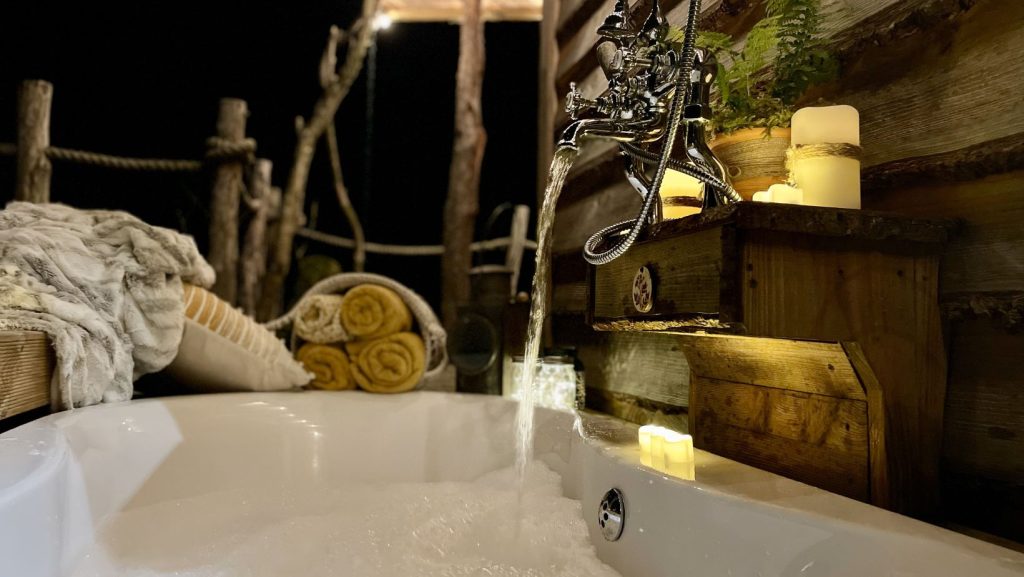 Outdoor bath with candles and warm lighting at Erwain Escapes, Luxury Glamping-Cabin-Carmarthenshire-West-Wales
